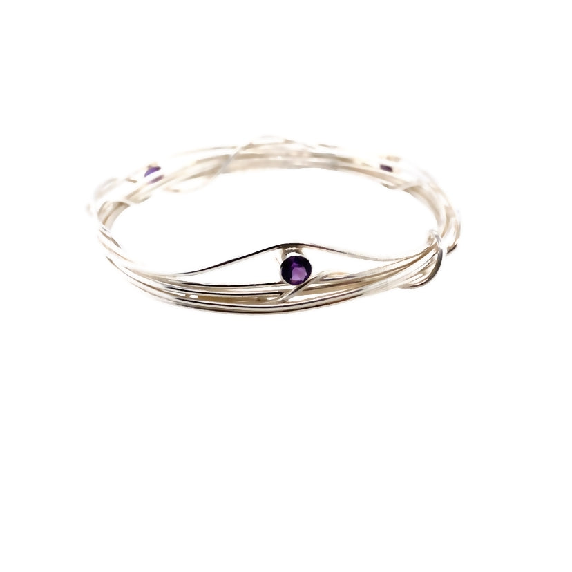 Three faceted amethyst stones set on a silver wrap bangle