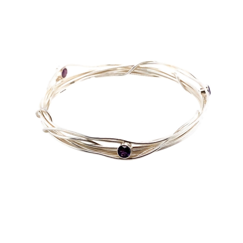 Three faceted amethyst stones set on a silver wrap bangle