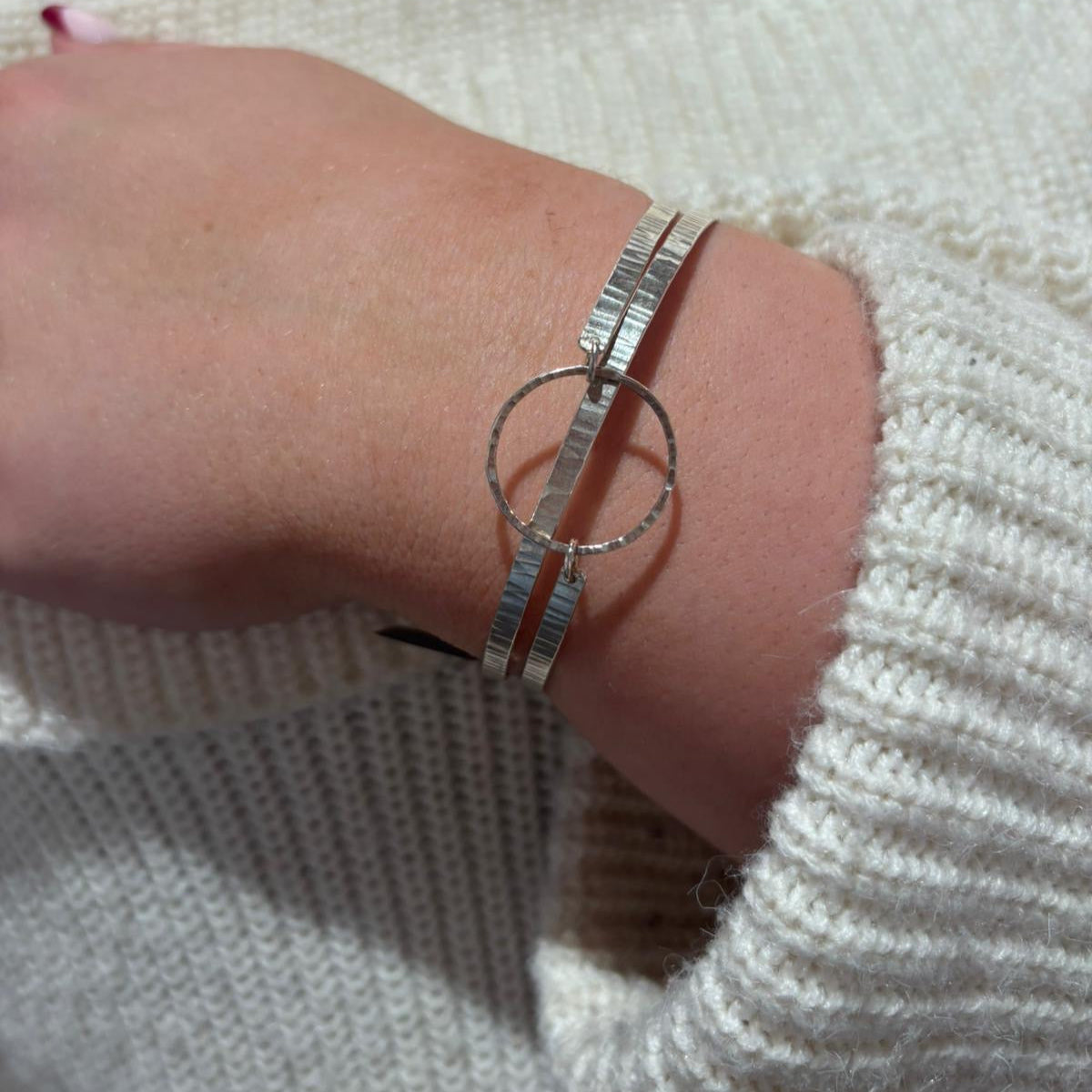 Silver bracelet on a wrist with a neutral background