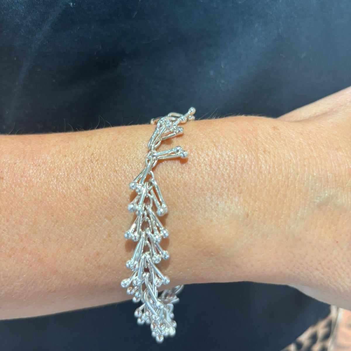 Silver bracelet on a wrist against a dark background