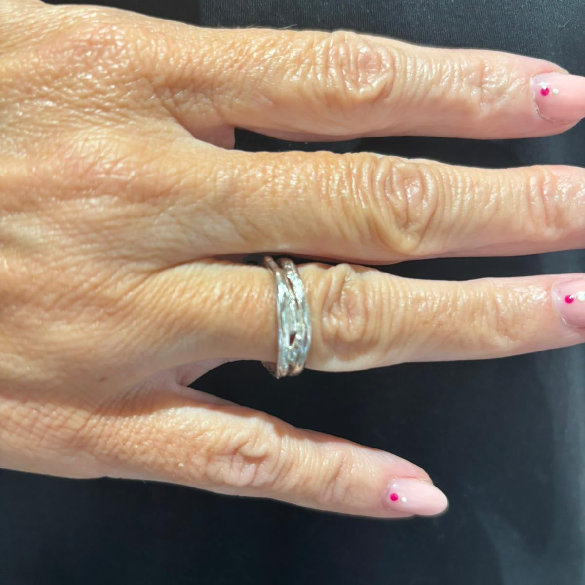 Hand wearing a silver ring on a plain background