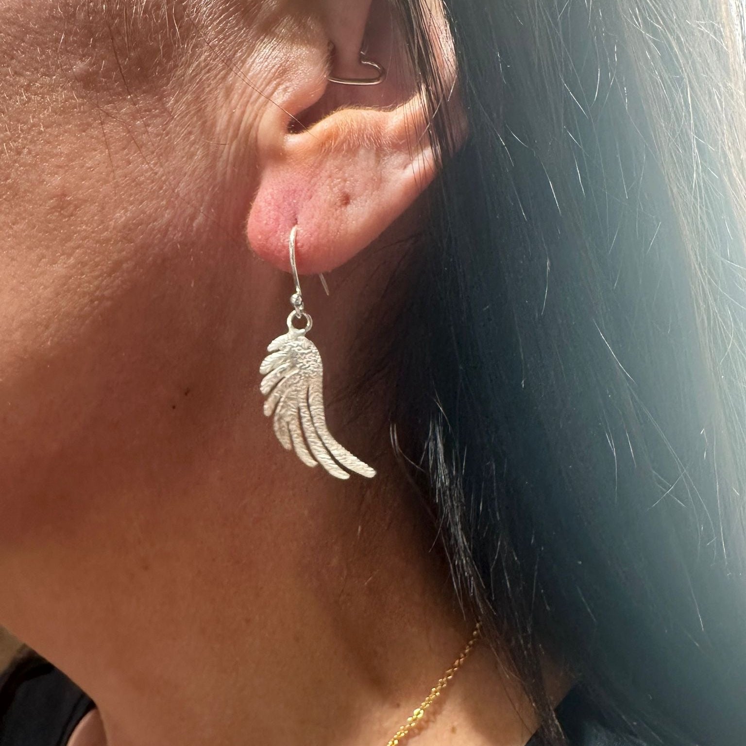 Close-up of a person wearing a silver Wing-shaped earring.
